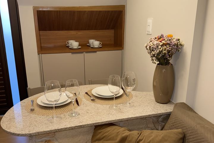 Nicho de madeira, bancada de pedra com mesa posta e vaso de flores
