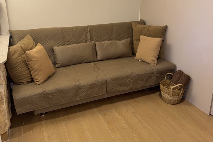 Sofá-cama com almofadas e cesto ao lado