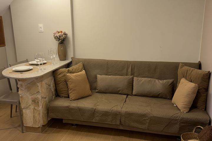 Sofá-cama e bancada de pedra com vaso de flores