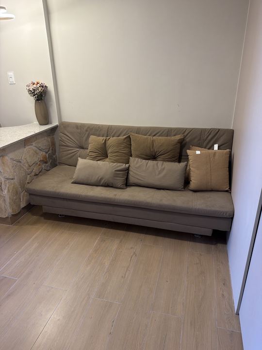 Sofá-cama com almofadas sobre piso amadeirado