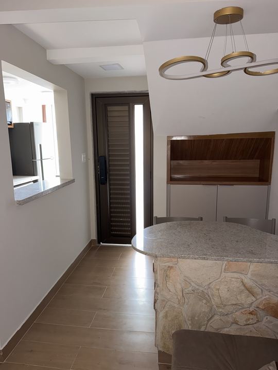 Entrada com porta de madeira, luminária e mesa de pedra