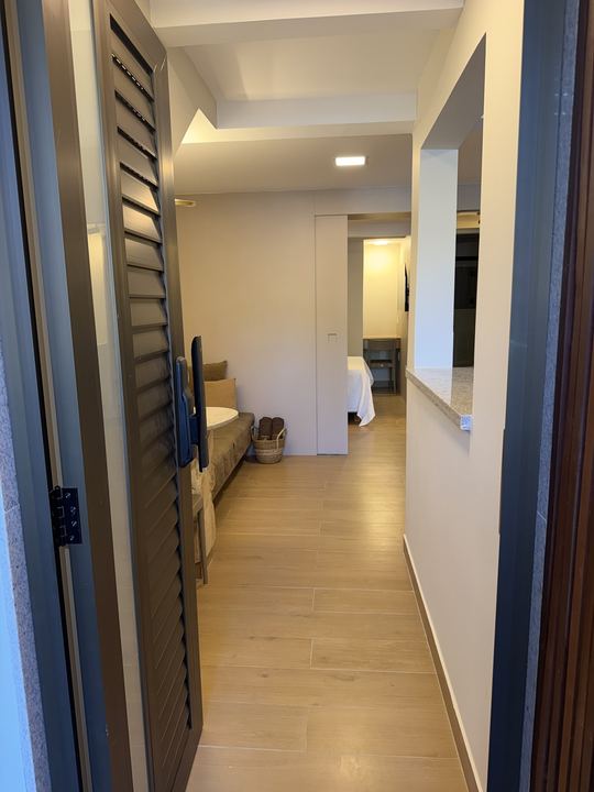 Corredor interno com persiana de madeira e quarto ao fundo