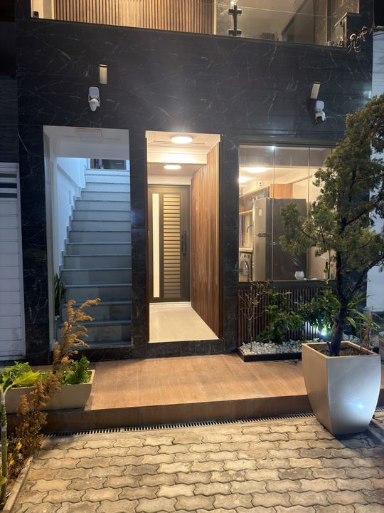 Entrada iluminada à noite com escada e jardim